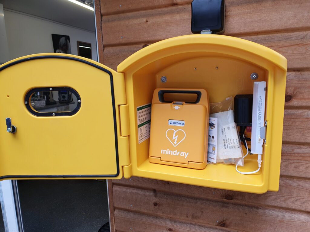 Yellow AED defibrillator box with Mindray AED device installed, mounted on a wall for emergency use