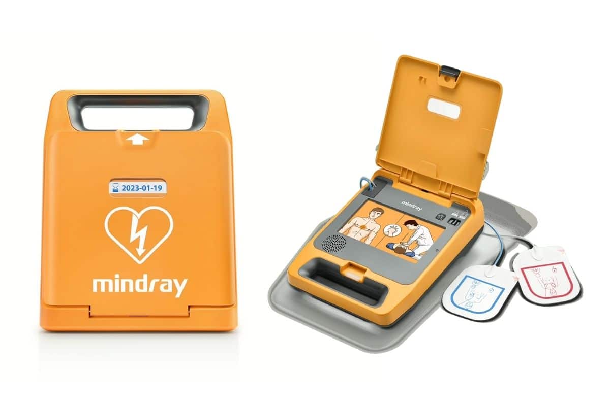 An orange C1A Mindray defibrillator in its closed case next to an open defibrillator showing connected pads and simple usage illustrations.