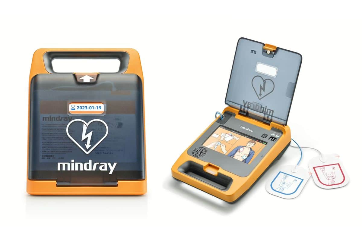 The C2 Mindray defibrillator in an orange and dark translucent case next to an open version showing instruction images and connected pads.