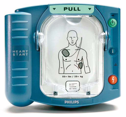 A close-up view of the Philips HeartStart HS1 defibrillator with the lid open, showing the electrode pads and a graphic for proper placement on a patient’s chest. The "Pull" tab is visible, signaling for activation.
