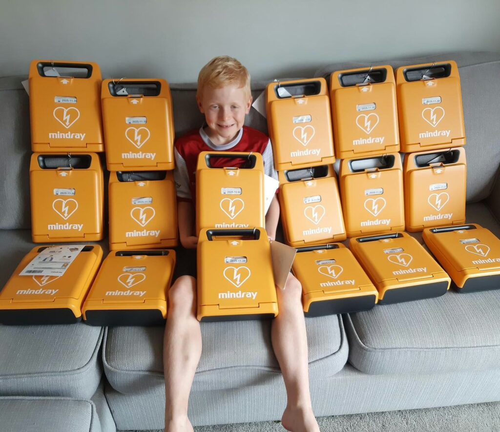 Young child surrounded by multiple Mindray AED defibrillators, highlighting the importance of having AEDs readily available.
