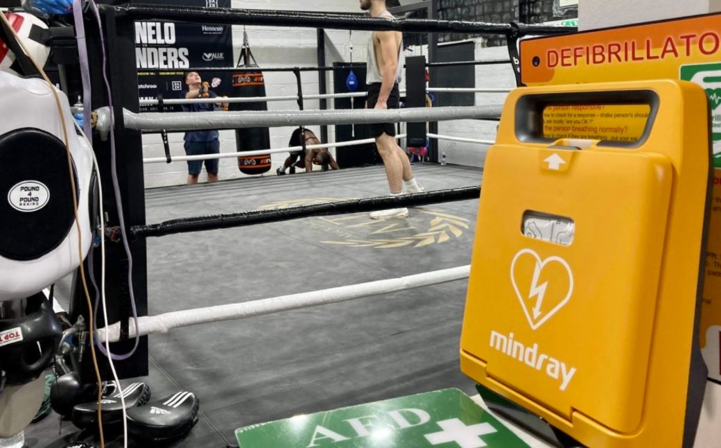 A Mindray defibrillator mounted in a boxing gym next to the ring, ready for emergency use during intense training sessions.