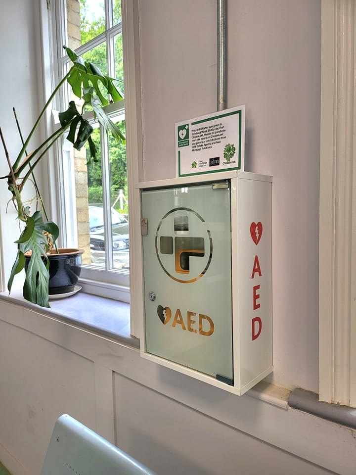 Wall-mounted AED in a glass case with AED signage, showing its readiness for use in emergencies, featured in the post 'How to Create a Cardiac Emergency Response Plan for Your Business'