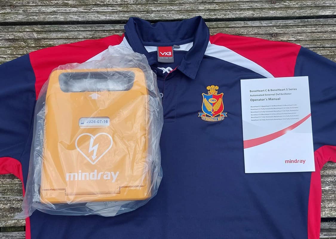 A new AED device from Mindray next to a sports shirt and the operator's manual.