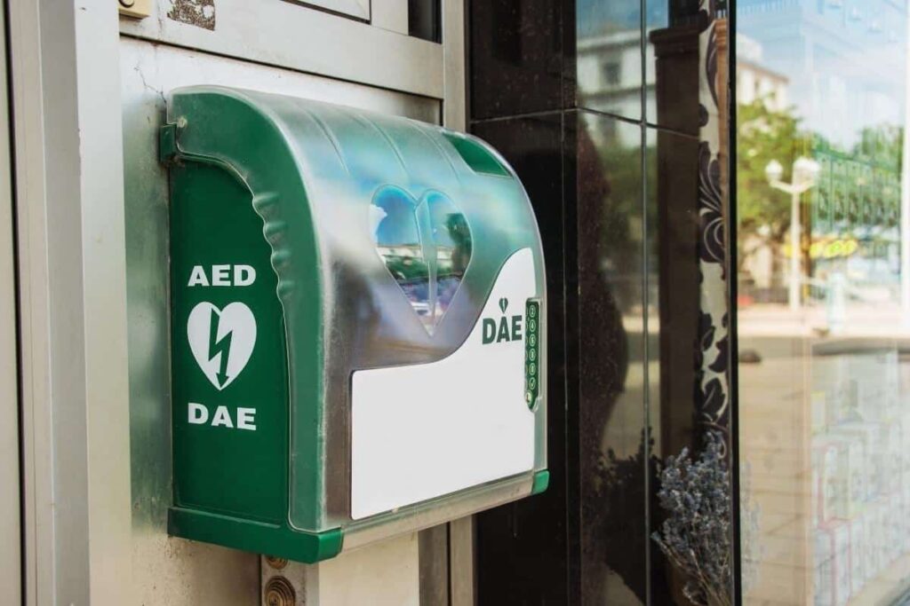 An AED Defibrillator mounted on a wall outdoors.
