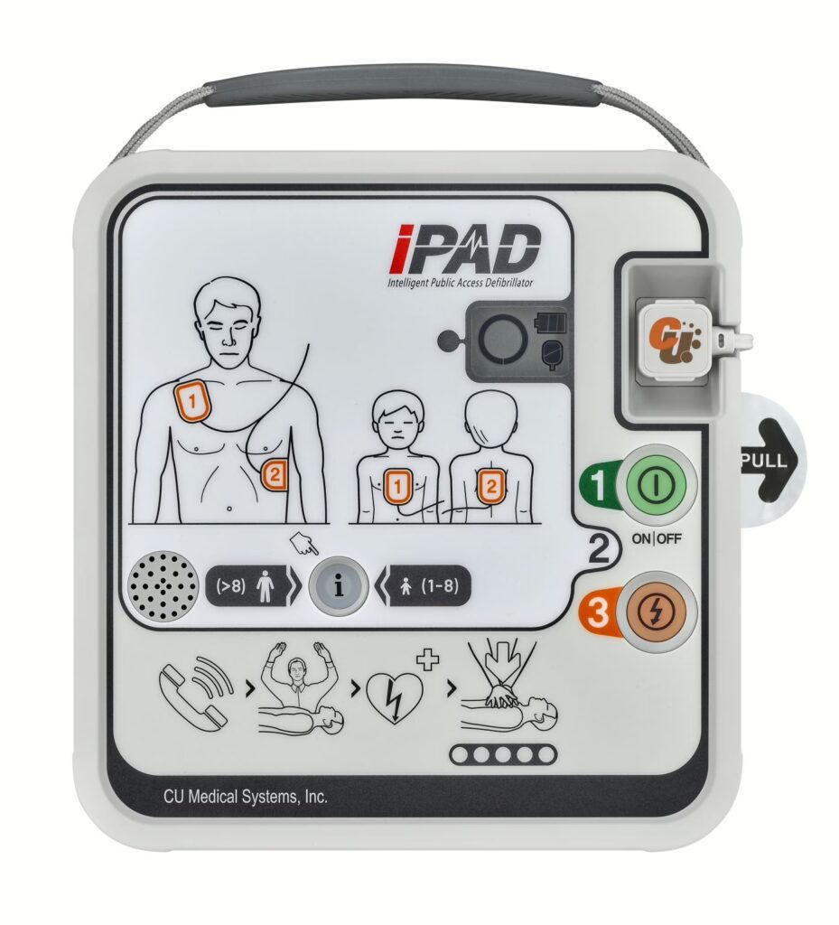 Close-up of the iPAD SPR Semi-Automatic Defibrillator control panel, showing the user interface with instructions for adult and child patient placement, buttons for power, settings, and shock delivery.