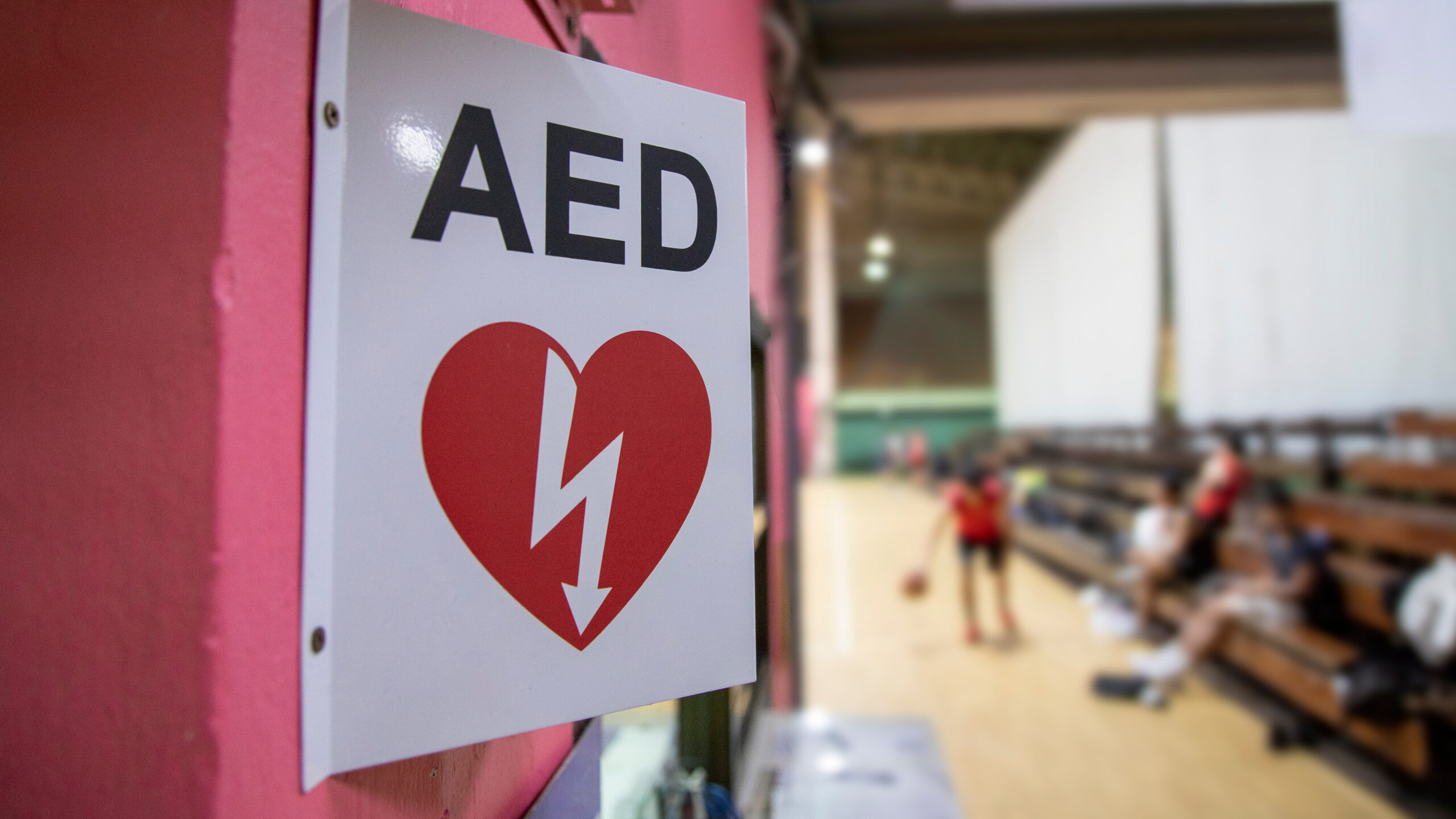 AED sign indicating the location of an Automated External Defibrillator in a sports facility. This image highlights the importance of AED accessibility in high-traffic areas like gyms, where quick action can save lives in the event of a cardiac emergency.
