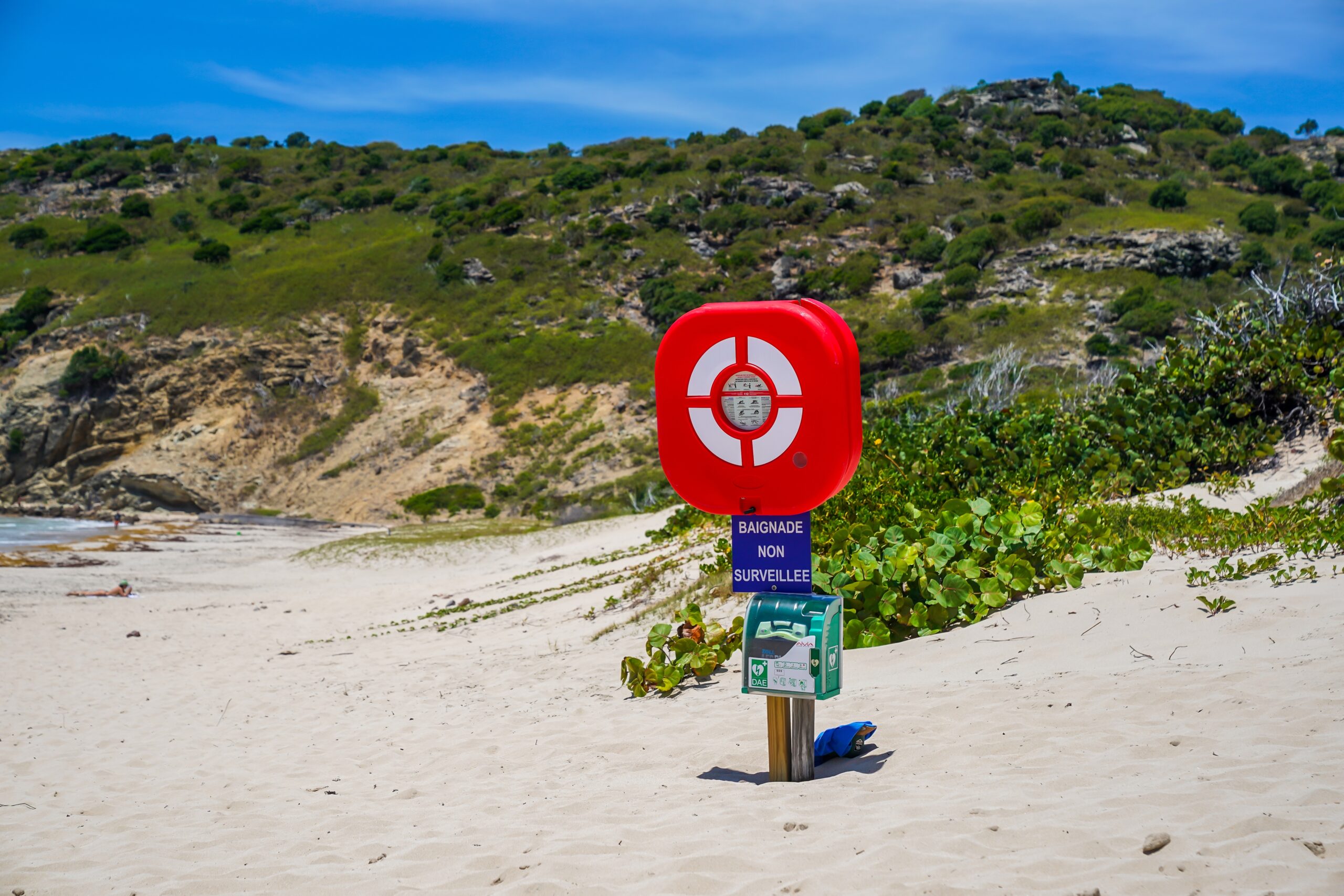 Defibrillator mounted on a signpost at a beach with a lifebuoy, showcasing the importance of having AEDs in remote or less-obvious places